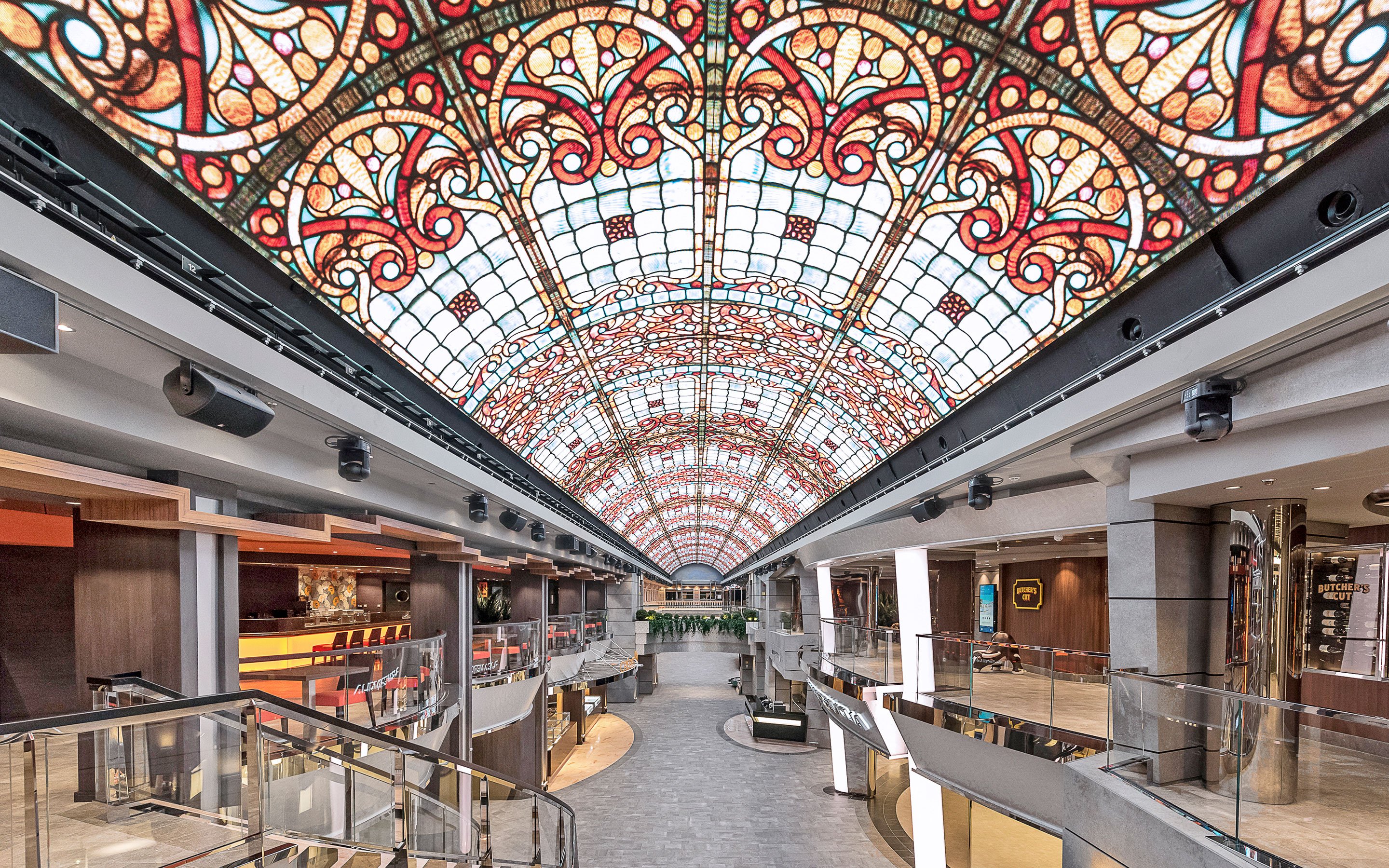 Luxurious cruise ship promenade with vibrant stained-glass ceiling and upscale shops | MSC Cruises